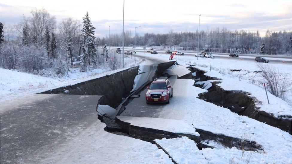 A stranded vehicle lies on a collapsed roadway near the airport after an earthquake in Anchorage