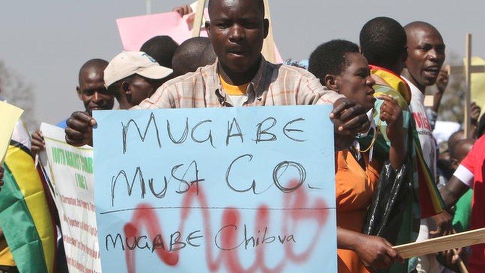 Protesters in Harare, Zimbabwe, one holding a "Mugabe must go" sign and others holding wooden crosses - Wednesday 3 August 2016