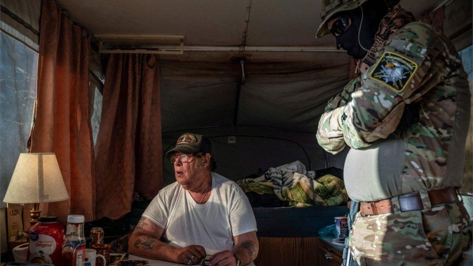 In this file photo taken on March 20, 2019 Striker (L), the leader of the Constitutional Patriots New Mexico Border Ops Team militia, speaks with Viper (R), who go by aliases to protect their identity, inside the team"s camper while discussing logistics on a group chat near the US-Mexico border in Anapra, New Mexico. - The FBI has arrested a member of an armed rightwing militia group accused of illegally detaining migrants at the US-Mexico border, officials said on April 20, 2019. New Mexico Attorney General Hector Balderas described Larry Mitchell Hopkins, who also goes by the name of "Striker," as a "dangerous felon who should not have weapons around children and families."