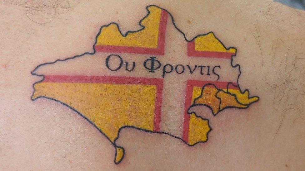 Tattoo of a Dorset map infilled with the county's flag and Greek writing