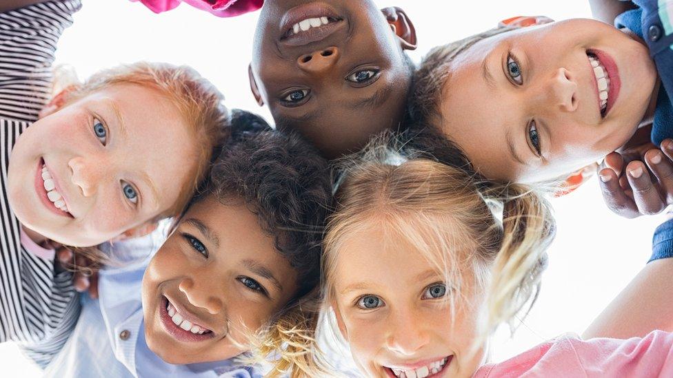 five children with all their heads together looking down at camera