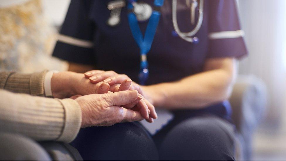 Carer in uniform holding a woman's hands