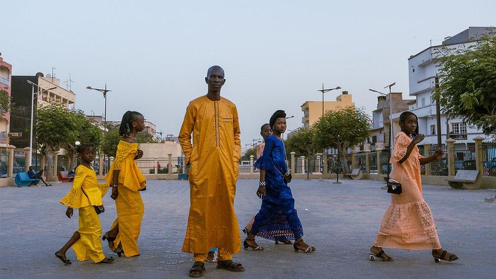 Taxi driver Fallou Sene poses for the camera in an orange boubou