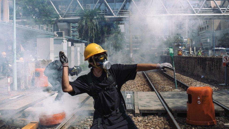 A protester throw a stone towards police outside Tin Shui Wai police station during a protest on August 05