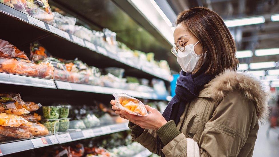 Stock image of a woman buying vegetables in the supermarket