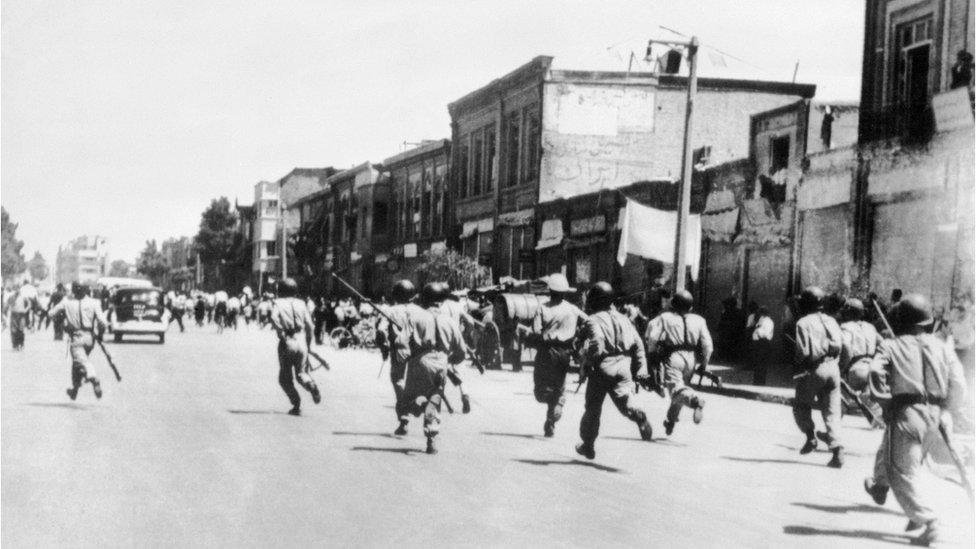 old photo of soldiers chasing rioters through the streets of Tehran