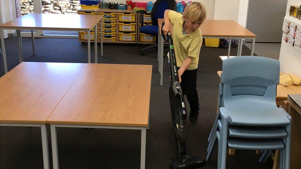 Child vacuuming classroom