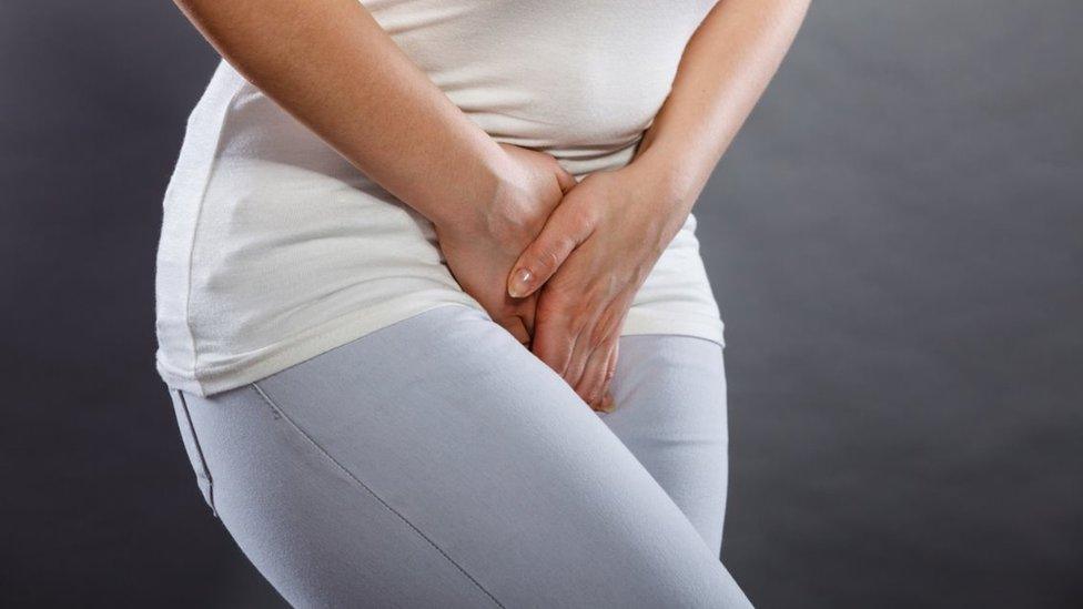 Stock image of a clothed woman holding her crotch area