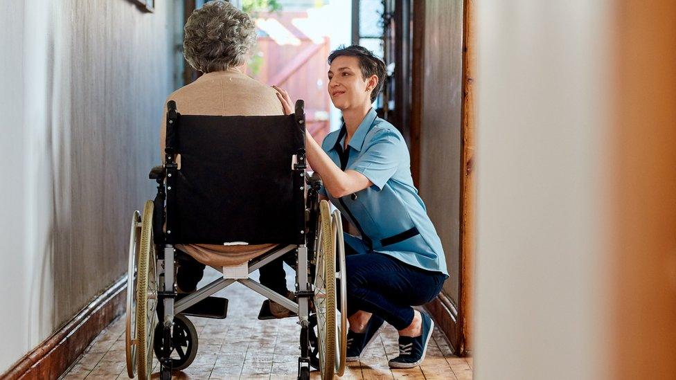 Carer helps woman in wheelchair