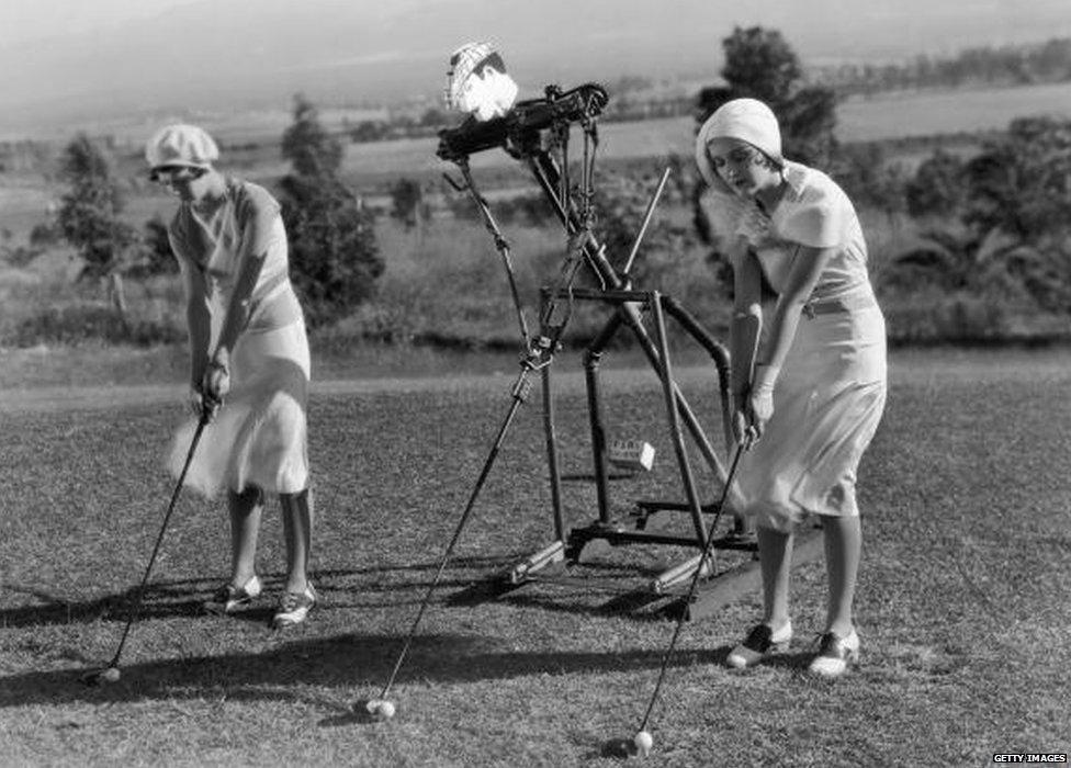 Two golfers use a golf robot trainer to help with their golf swing.