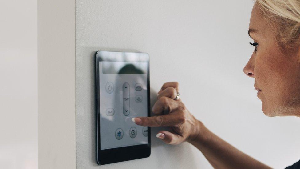 Woman adjusting thermostat