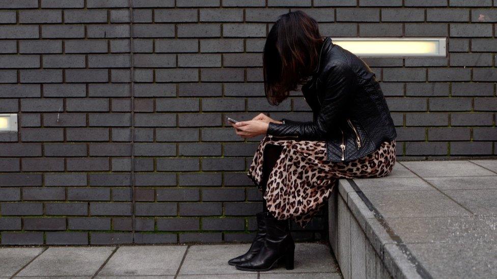 Woman on phone, sitting on step