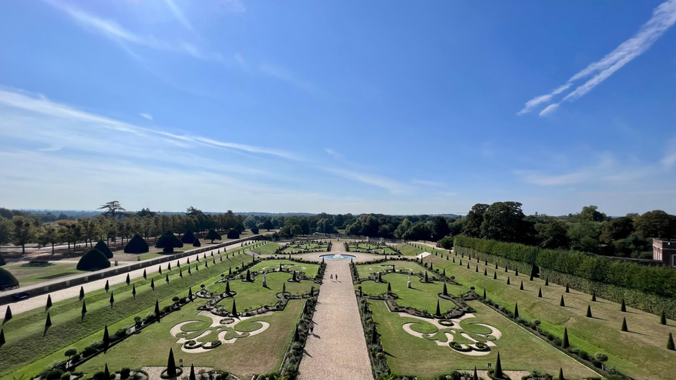 Picture of the gardens of Hampton Court in London with blue skies overhead.