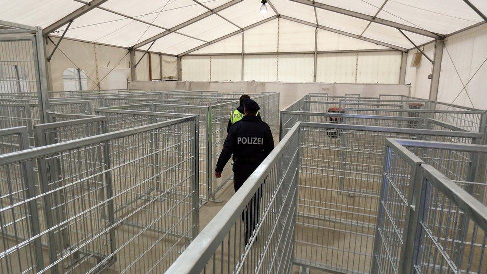 Two policeman walk in an empty registration tent for migrants at the border to Slovenia in Spielfeld, Austria