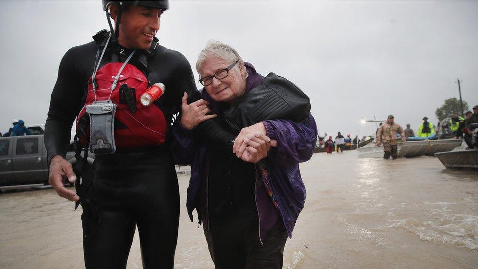 A man rescues a woman from her flooded neighbourhood in Houston, Texas.