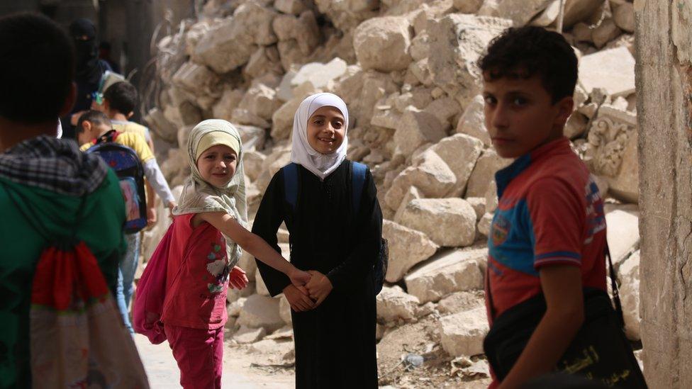 On 21 September 2016 in eastern Aleppo Judy (white head scarf), 9, and her schoolmates walk to school past the rubble of nearby houses.