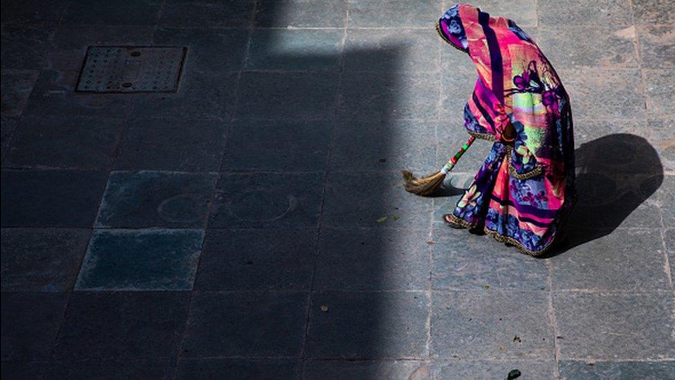 An Indian woman sweeps her home