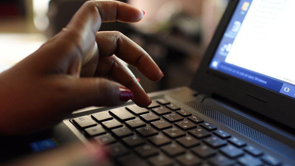 A hand typing on a laptop