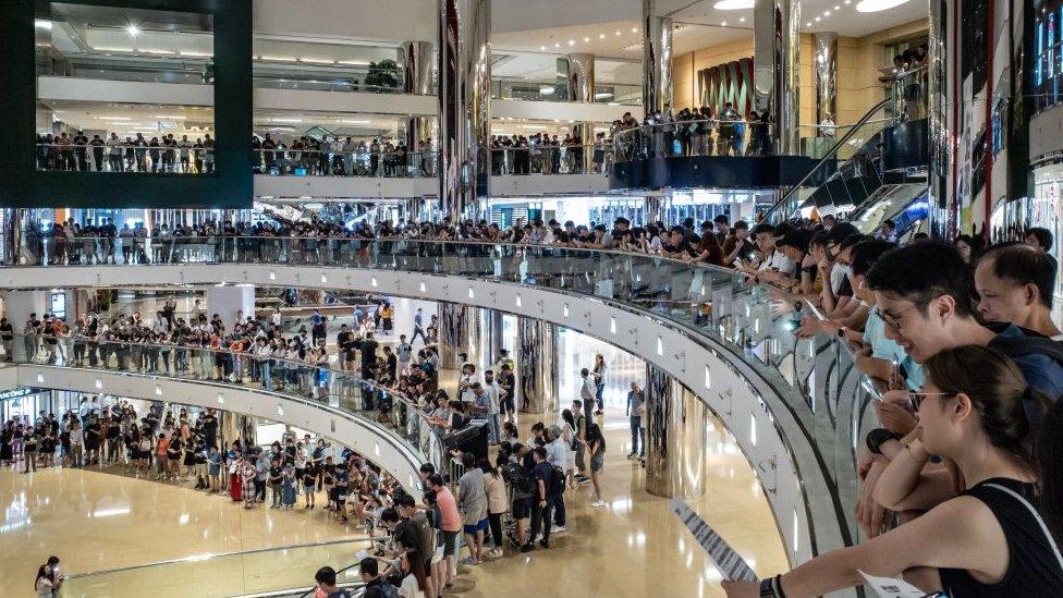 Residents and protesters sing songs and shout slogans as they gather at a shopping mall after business hours in Tai Koo district