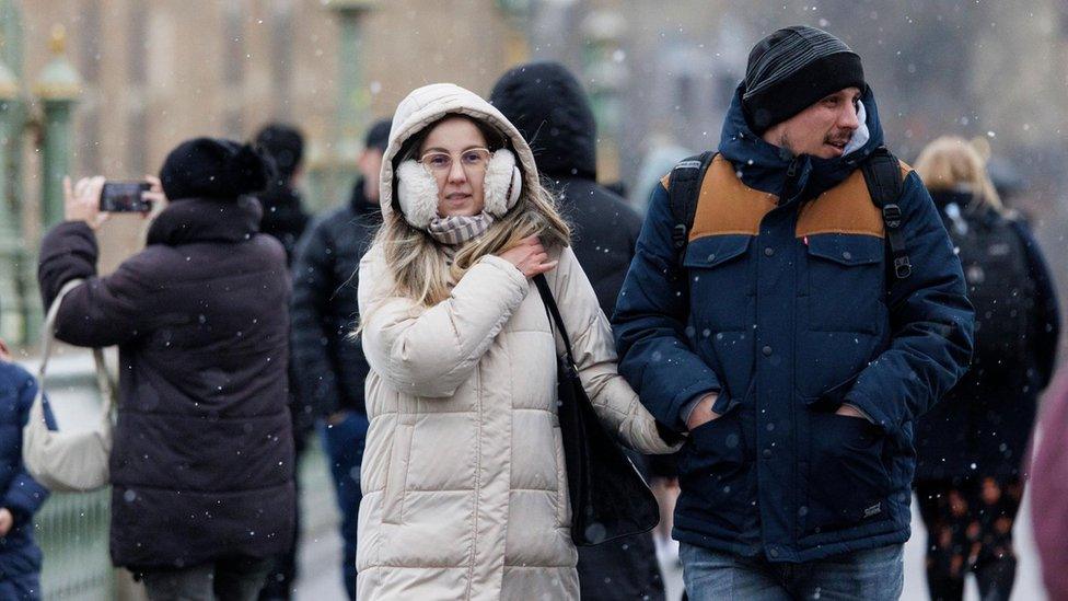 People walk through a snow flurry on Westminster Bridge in London, Britain on Monday