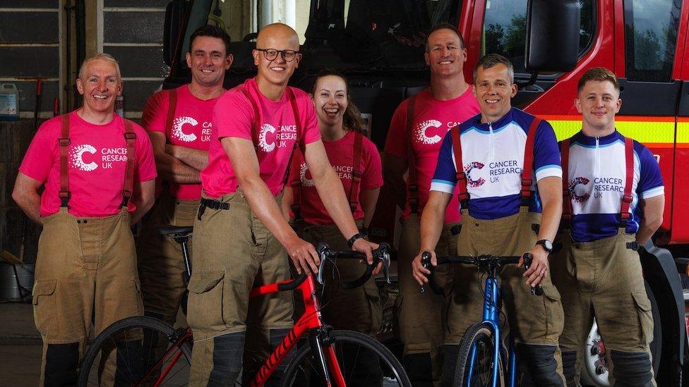 Seven firefighters from Avon Fire and Rescue standing in front of a fire engine. They are all wearing Cancer Research UK t-shirts. Two of the men are stood with bikes.