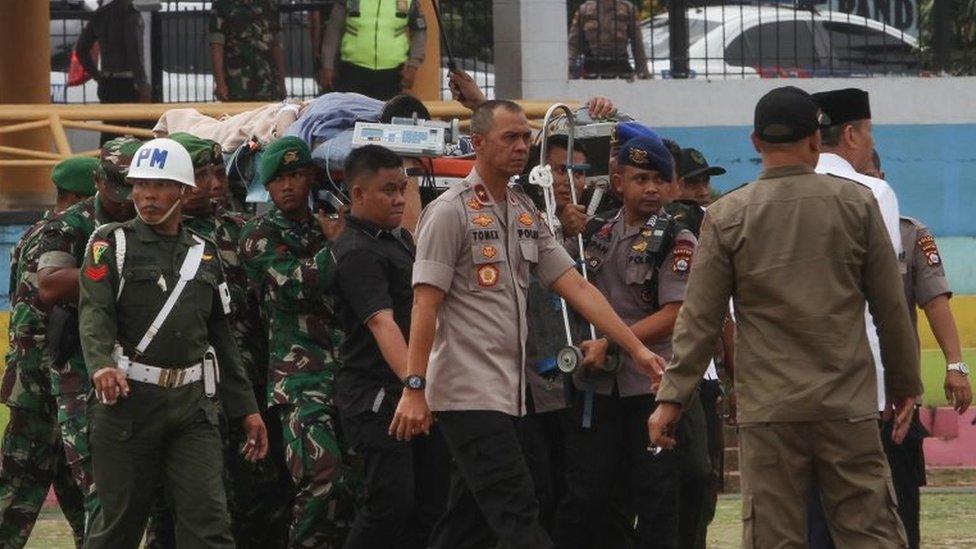 Indonesian police and military carry Wiranto on a stretcher to a helicopter