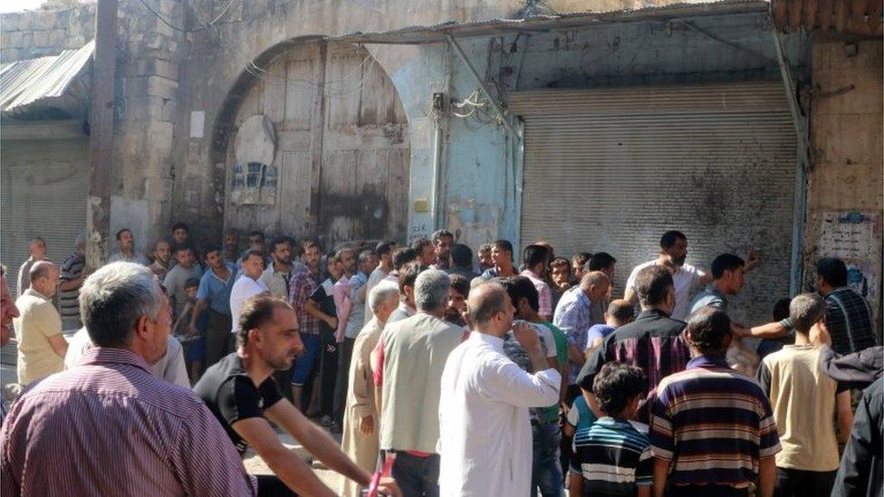 Men wait in line to receive food aid in Aleppo, Syria 10/08/2016