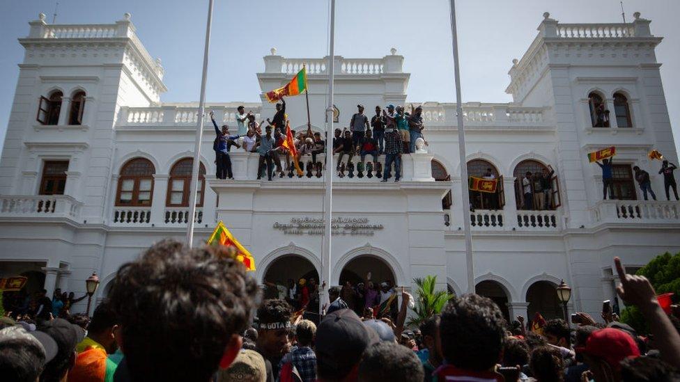 Protestors wave flags and chant slogans after taking control of the Prime Ministers office compound during a protest seeking the ouster of Sri Lanka's Prime Minister Ranil Wickremesinghe amidst the ongoing economic crisis on July 13, 2022 in Colombo, Sri Lanka.