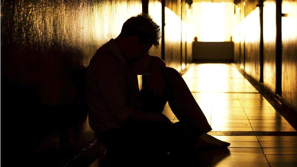 A man silhouetted and sat on the ground