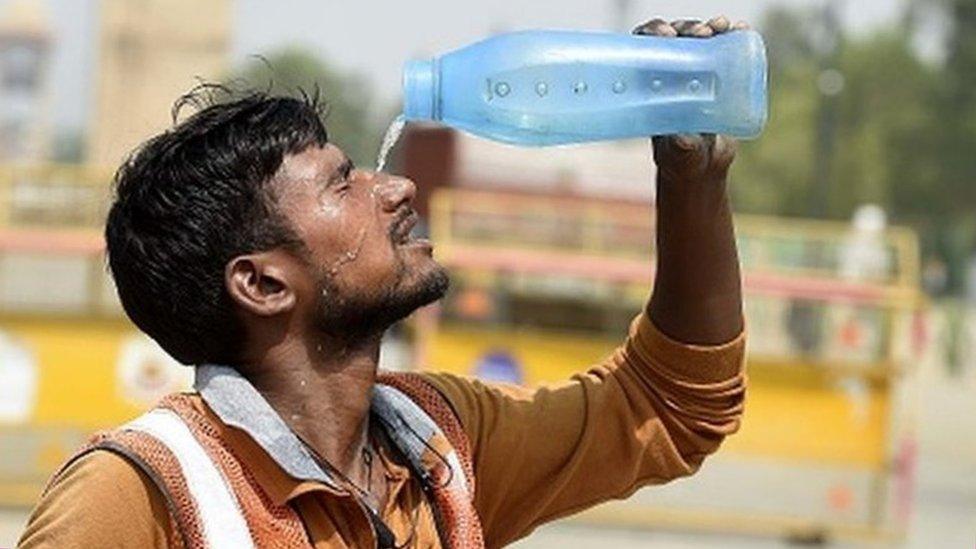 A worker pours water amid the scorching heat near India Gate in Delhi