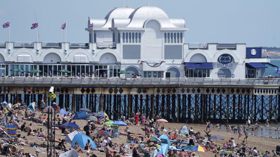 People gather in the sun by a pier