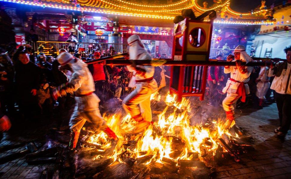 Performers carry a sedan chair made with palm and jump on a fire - a traditional custom for the Lantern Festival in Putian, Fujian Province