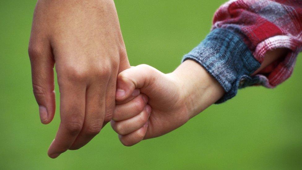 Child holding adult's hand