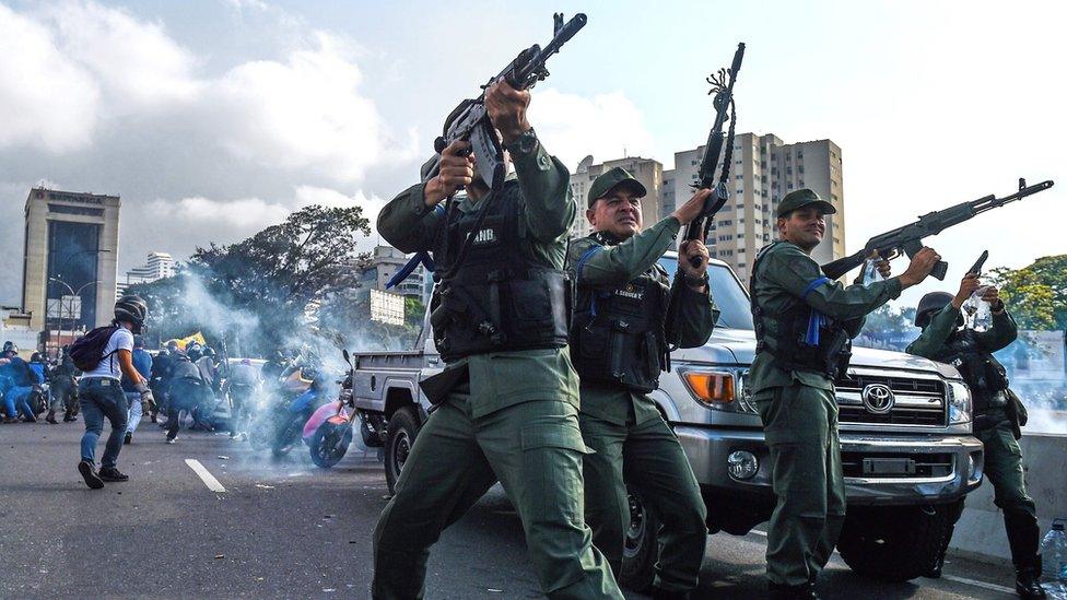 Members of the Bolivarian National Guard who joined Venezuelan opposition leader and self-proclaimed acting president Juan Guaido fire into the air to repel forces loyal to President Nicolas Maduro who arrived to disperse a demonstration near La Carlota military base in Caracas on April 30, 2019