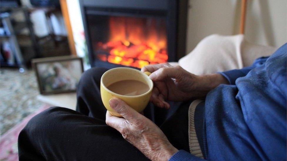 A man warms himself in front of a fire