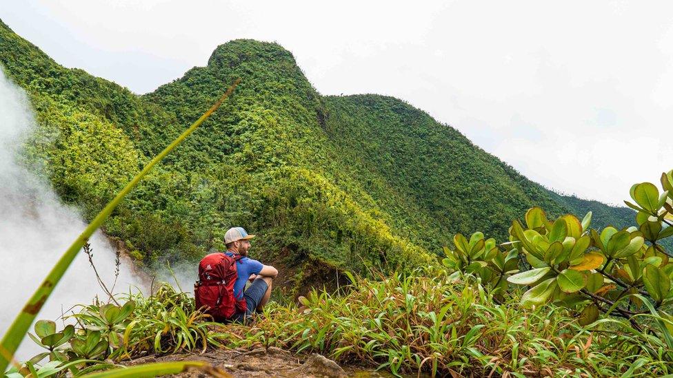 A man on a green mountainside in Dominica