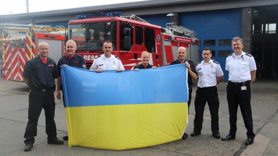 Firefighters holding a Ukrainian flag