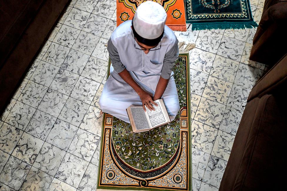 A worshipper reads the Koran at his house