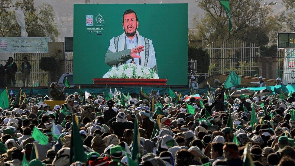 People watch as Houthi leader Abdul Malik al-Houthi delivers a speech on a TV screen during a rally marking the birthday of Prophet Muhammad in Sanaa, Yemen (29 October 2020)