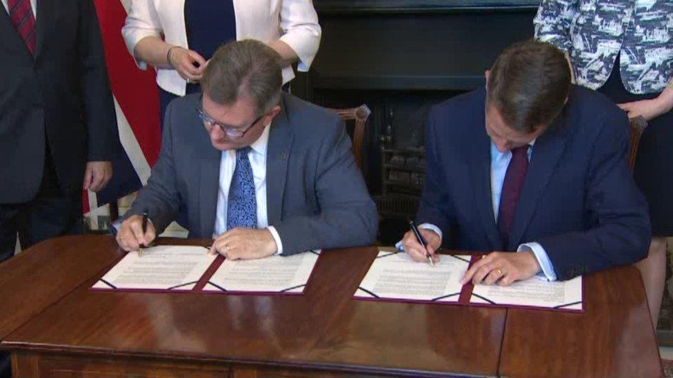 The DUP's Sir Jeffrey Donaldson and Gavin Williamson of the Conservative Party sign a deal in Downing Street