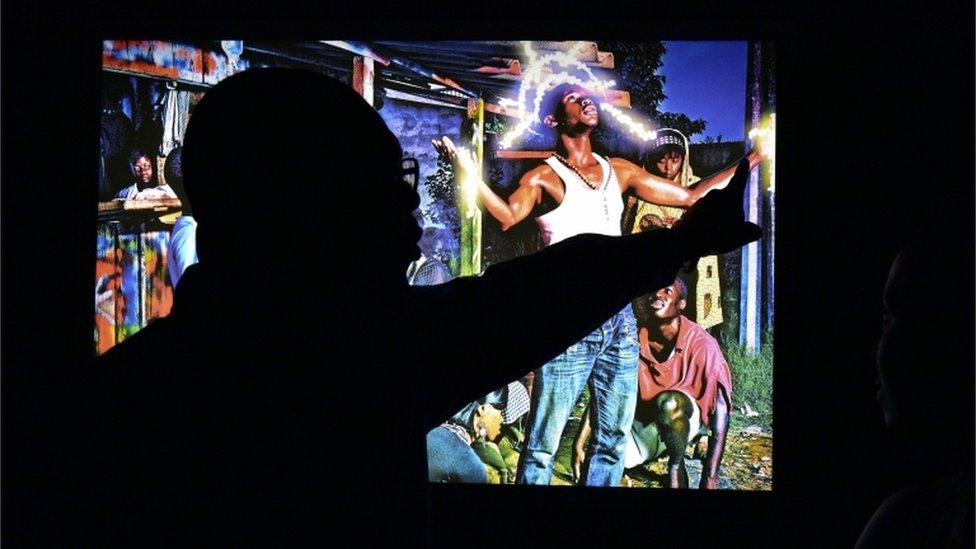 A visitor looks at an artwork during the opening of the exhibition Lumieres dAfriques (Lights of Africa) at the Charles Donwahi Foundation in Abidjan on April 26, 2016. The exhibition conceived by African Artists for Development (ADD) displays artworks including photographs, paintings and sculptures by 54 African artists, one from each country of the continent, who have created their pieces inspired by the theme The Illuminated Africa. The exhibiton runs from April 27 to June 6, 2016