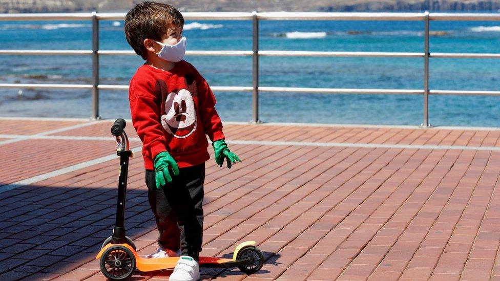 A child plays with a scooter at promenade of Las Canteras beach after restrictions were partially lifted for children for the first time in six weeks