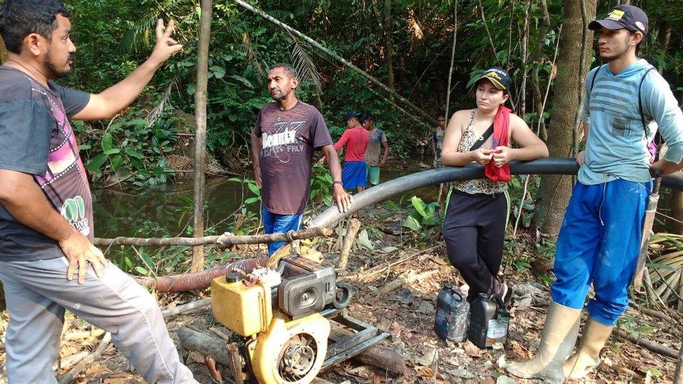 Ageu Pereira (left), the president of the community of Montanha and Mangabal, explains to gold miners that the land belongs to the community