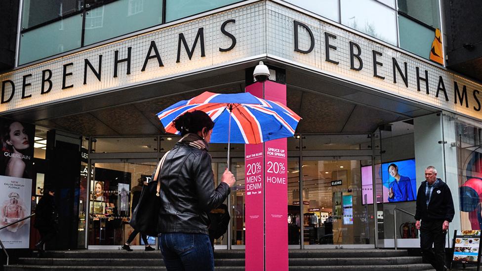 Shoppers walk past a Debenhams shop