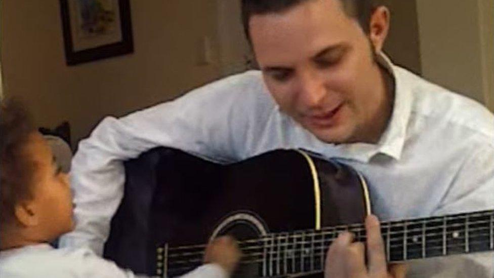 Nandi Bushell as a toddler strumming a guitar with her father John