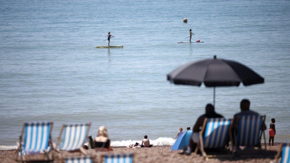 People paddle board as they enjoy the hot weather at Brighton beach