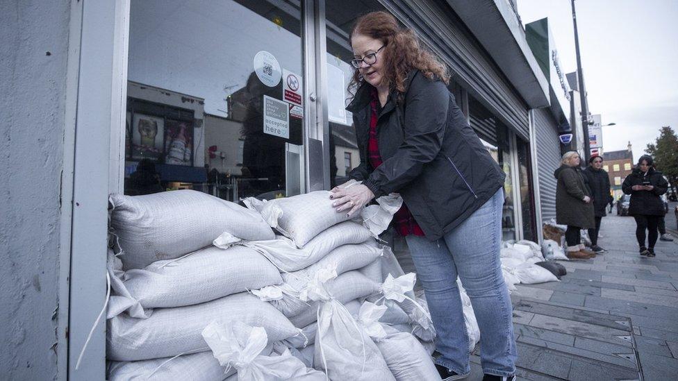 Woman stacking sandbags against a door in Downpatrick