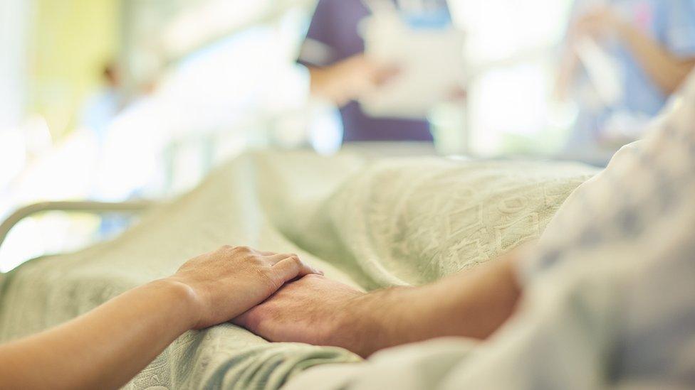 Patients holding hands at hospital bedside