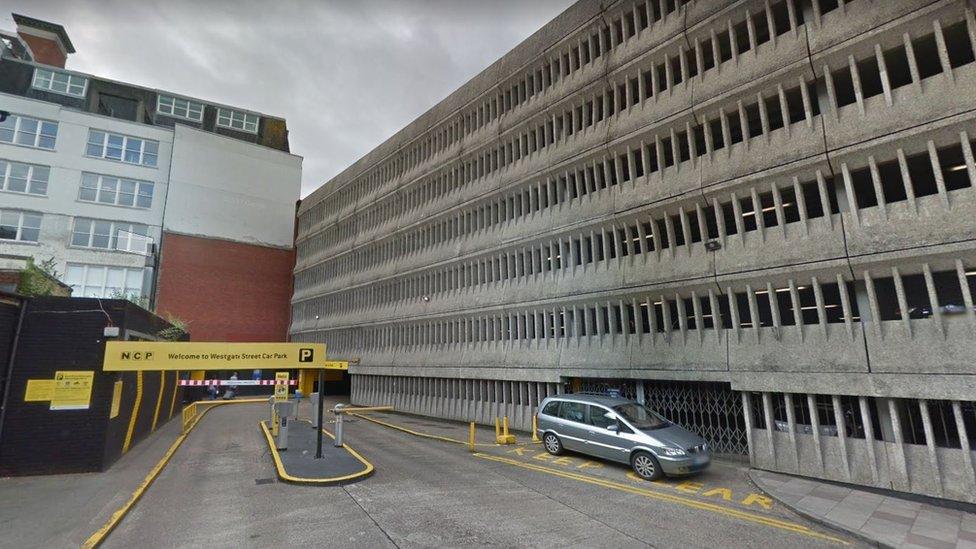 A picture of a multi storey car park. There is a yellow sign with NCP written on it and a barrier