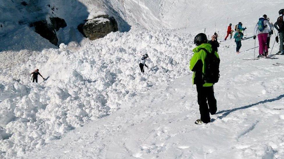 People dig through piles of snow